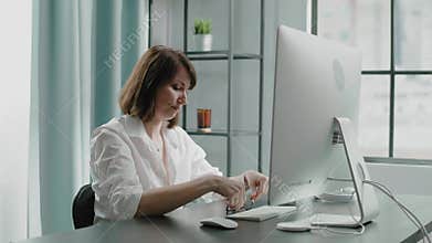 Tired lady boss puts on glasses to work on computer at table