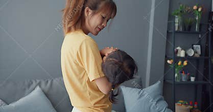 Happy cheerful Asia family mom holding toddler girl cry in arms and comfort care walking in living room at house. Spending time