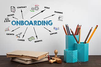ONBOARDING. Office supplies and books on a wooden table