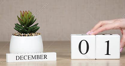 Wooden calendar with an important event for December 1, a woman`s hand sets the date on the calendar. Winter season.