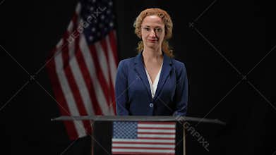 Confident beautiful American politician woman standing at tribune looking at camera. Portrait of intelligent elegant