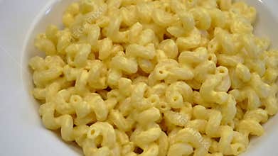 Mac and cheese pasta. American style Italian pasta with cheddar cheese on a white plate. Food video