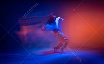 Dancing female standing on tiptoe in colourful neon studio light. Long exposure. Contemporary hip hop dance