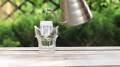 The process of brewing coffee. Water is poured into a drip coffee bag in a mug.