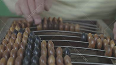 Close up of elderly hand moving beads on abacus. Focus on traditional counting method highlights nostalgia and manual