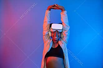 Young African sport woman wearing VR stretching whole body posing. Contrivance.