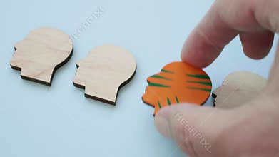 A hand replaces identical heads with a unique colorful one. Individuality and creativity.