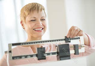Happy Woman Adjusting Balance Weight Scale