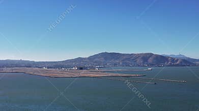 Aerial view of a plane landing at San Francisco International Airport, with runway and surrounding San Francisco Bay under a clear