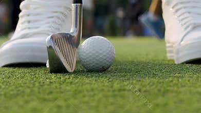 Golfer comes up to hit small ball with shiny driver on course