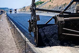 Industrial pavement truck laying fresh asphalt