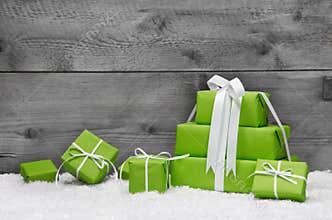 Stack of green Christmas presents, with snow on grey