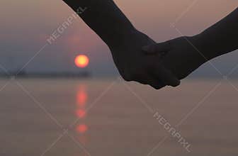 Couple holding hands at sunset