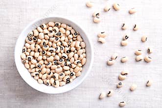 Dried black eyed peas in a white bowl over linen