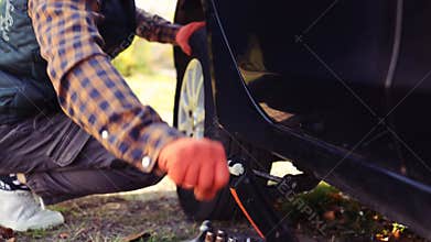 Caucasian man changing a tyre on his car. Changing wheel on car, spare tyre by the roadside.