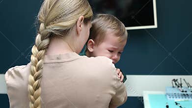 Mother comforting her crying baby son during a dentist appointment