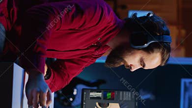 Vertical video Videographer color correcting clips while listening music in headphones