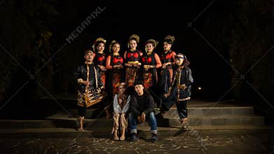 a group of dancers stand tall as red costumes provide a dramatic and graceful contrast