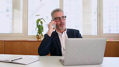 Contemporary middle aged businessman in smart casual wear talking on the smartphone