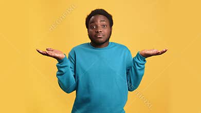 Doubtful African young man shrugging don't know not sure uncertain gesture posing isolated on orange