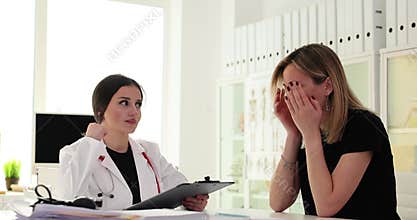 woman doctor sits at table and makes bad diagnosis to young patient