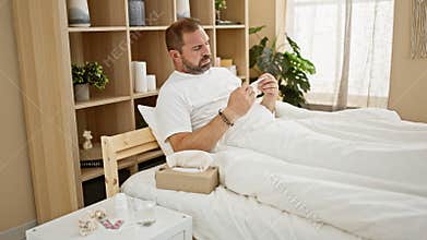 Middle-aged man with grey hair in a bedroom reaching for tissues, indicating sickness or allergies, in a cozy indoor setting