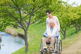 Senior man sitting on a wheelchair with caregiver