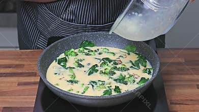 A woman pouring beaten eggs into a frying pan