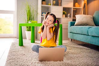 Photo portrait of cute small girl sit floor netbook look admire empty space dressed stylish yellow clothes modern
