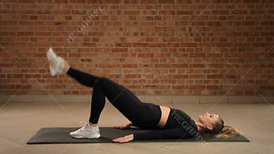 Expert fitness coach performing right single-leg hip bridge exercise