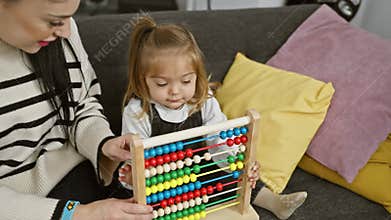 A woman and a young girl engage with an abacus in a cozy living room, symbolizing education and family bonding
