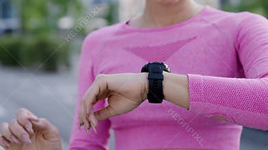 A young charming girl jogger outdoors in the city park among modern residential highrise buildings. A confident