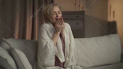 Woman Sneezing While Wrapped in a Blanket on a Couch at Home