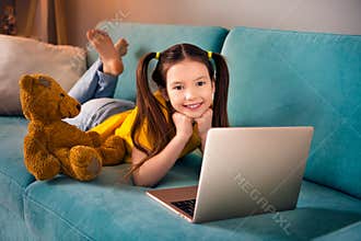 Photo portrait of cute small girl lying sofa have rest watch movie cartoon dressed stylish yellow clothes modern