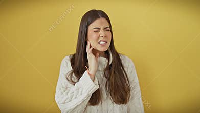 Hispanic young beauty in sweater, aching tooth pain visible on her face. standing isolated over yellow, hand touching mouth.