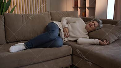 Elderly Woman Experiences Abdominal Pain On Couch