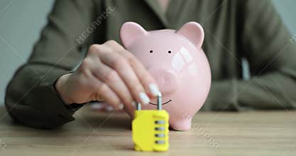 Woman hand puts combination lock in front of piggy bank