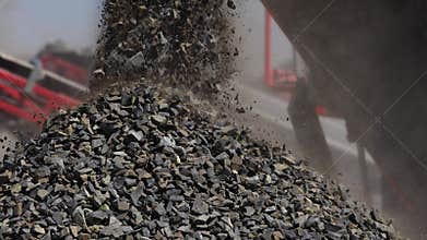 A powerful stream of crushed stone falling from a conveyor belt. Close-up.