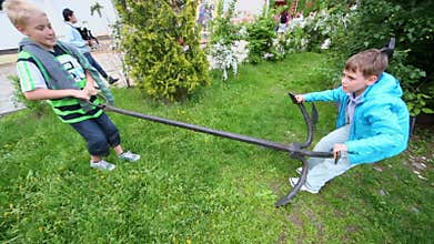 Two young boys try to raise huge anchor for ship