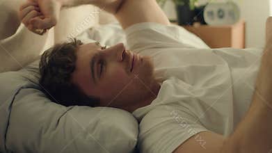 Man wake up lying bed bedroom stretching good morning happy male guy weekend home comfortable smile hotel orthopedic