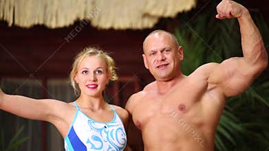 Muscular man and beautiful girl against bungalow