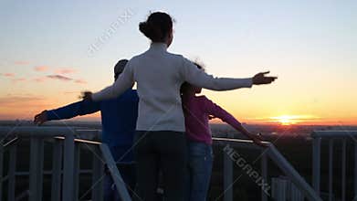 Back of mother, son and daughter with arms