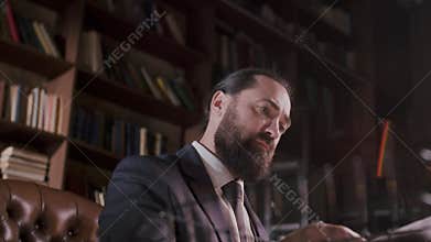 A businessman sits in a library, deeply focused, undisturbed by the surroundings
