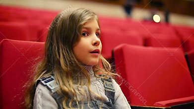 Pretty girl sits on red armchair in empty