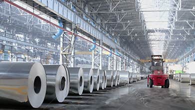 Loader machine rides by storage of aluminum rolls