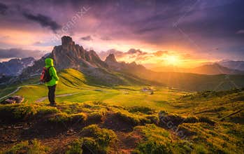 Woman with backpack and beautiful alpine mountain peaks at sunse