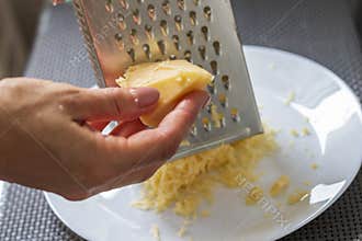 Shot of the woman grating hard cheese. Food
