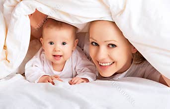 Happy family. Mother and baby playing under blanket