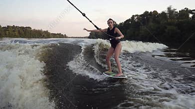 The girl rides on the water holding on to the rope with one hand.