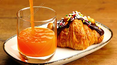 Pouring orange juice into transparent glass.